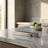 Modern kitchen counter with marble surface, bottle opener, and bowl of limes.