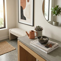 Small black bowl on a small table, books, teapot, and plant in a home setting.