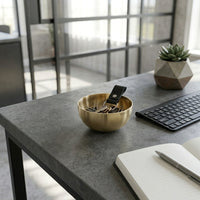 Brass key bowl on a desk with a keyboard and plant in the background