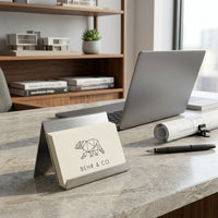 Desk setup with a laptop, notebook, and card holder with 'BEHR & CO.' branding.