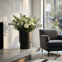 Modern interior with a vase of flowers on a table and a chair in the background.