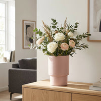 Pink vase with flowers on a wooden table in a living room