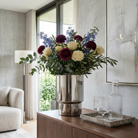 Floral arrangement in a silver vase on a wooden side table in a modern living room.