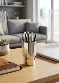 Modern home office desk with laptop, notebook, and pen holder.