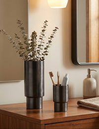 Bathroom counter with a vase, toothbrush holder, and soap dispenser.