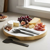 Cheeseboard with assorted meats, cheeses, fruits, and nuts on a light surface.