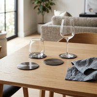 Two glasses on metal coasters with a modern living room in the background