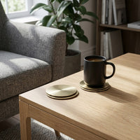 Coffee cup on metal coasters with a plant and sofa in the background