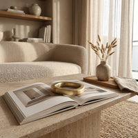 Living room with a textured sofa, coffee table, open book with a brass book weight and decorative items.