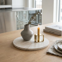 Decorative setup on a wooden table with a vase and a candle on a marble vase stand.