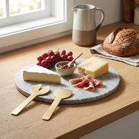 Platter of cheese, grapes, and cured meat on a tundra marble cheese tray with a pitcher in the background.