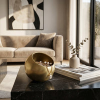 Gold jewelry holder on a marble coffee table with a couch and abstract art in the background
