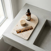Bottle, comb, and soap on a stone tray by a window