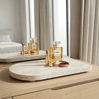 Chanel perfume bottle and lipstick on a stone tray with a neutral background